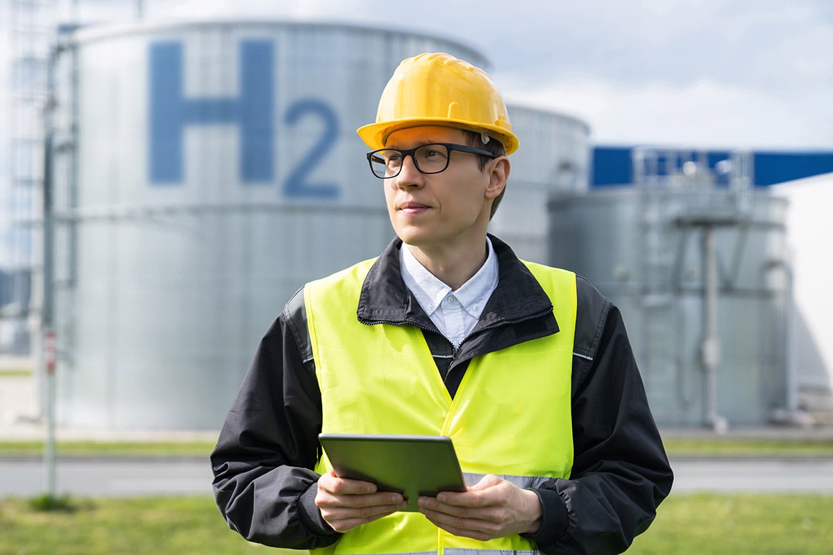 engineer man with tablet and behind h2 energy plant