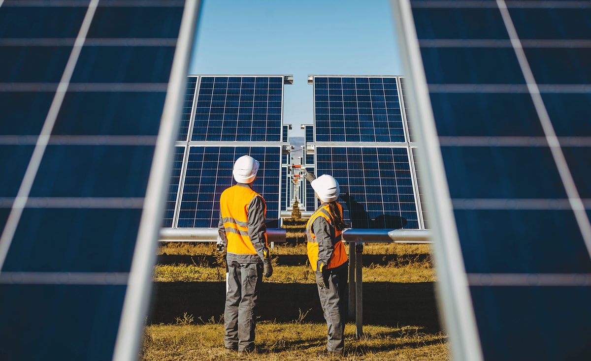 Two engineers standing middle of solar panels