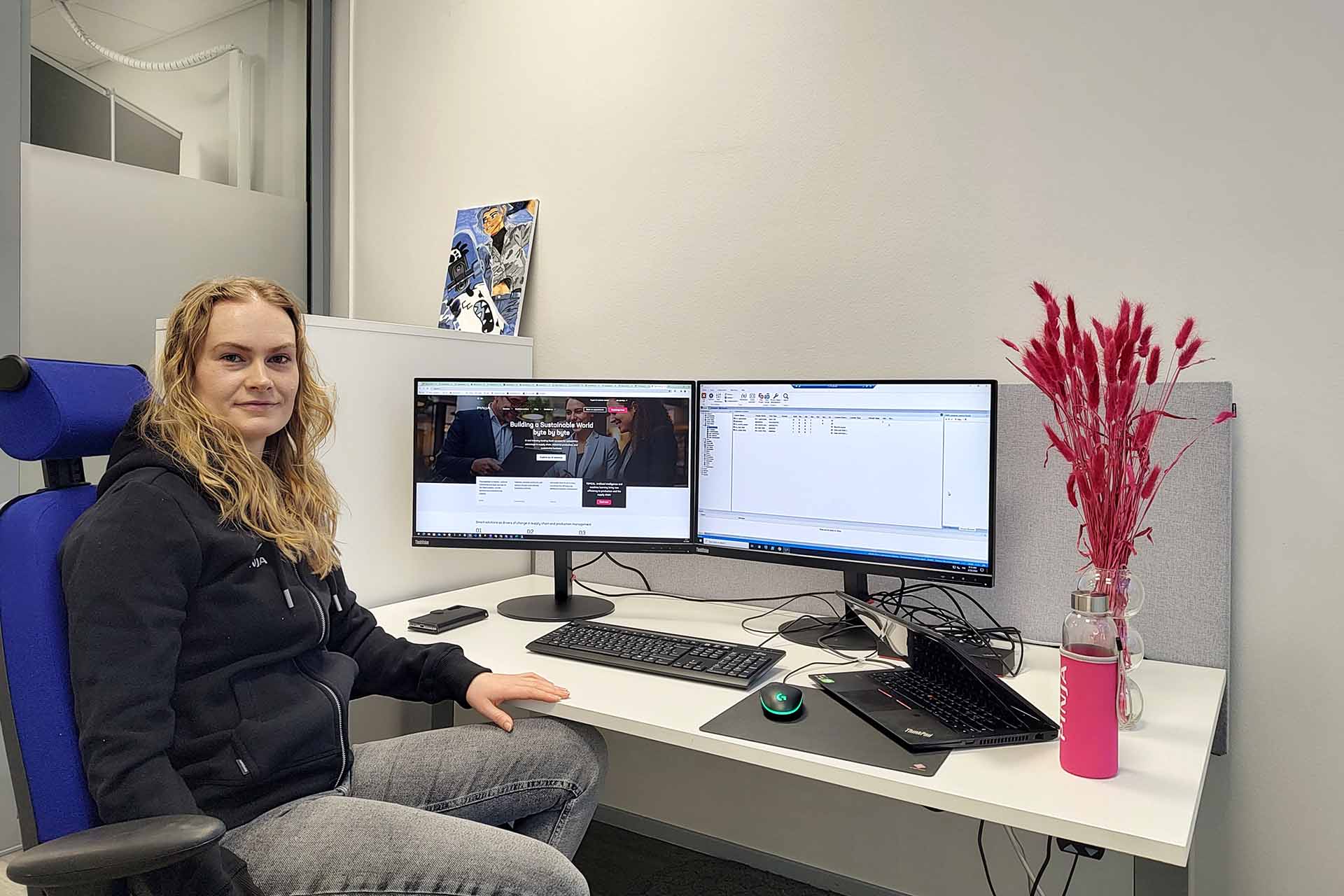 Blonde haired woman sitting in front of two screens at her desk