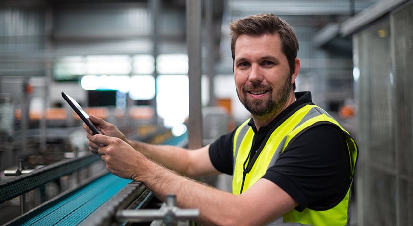 A man holds a tablet in a factory environment