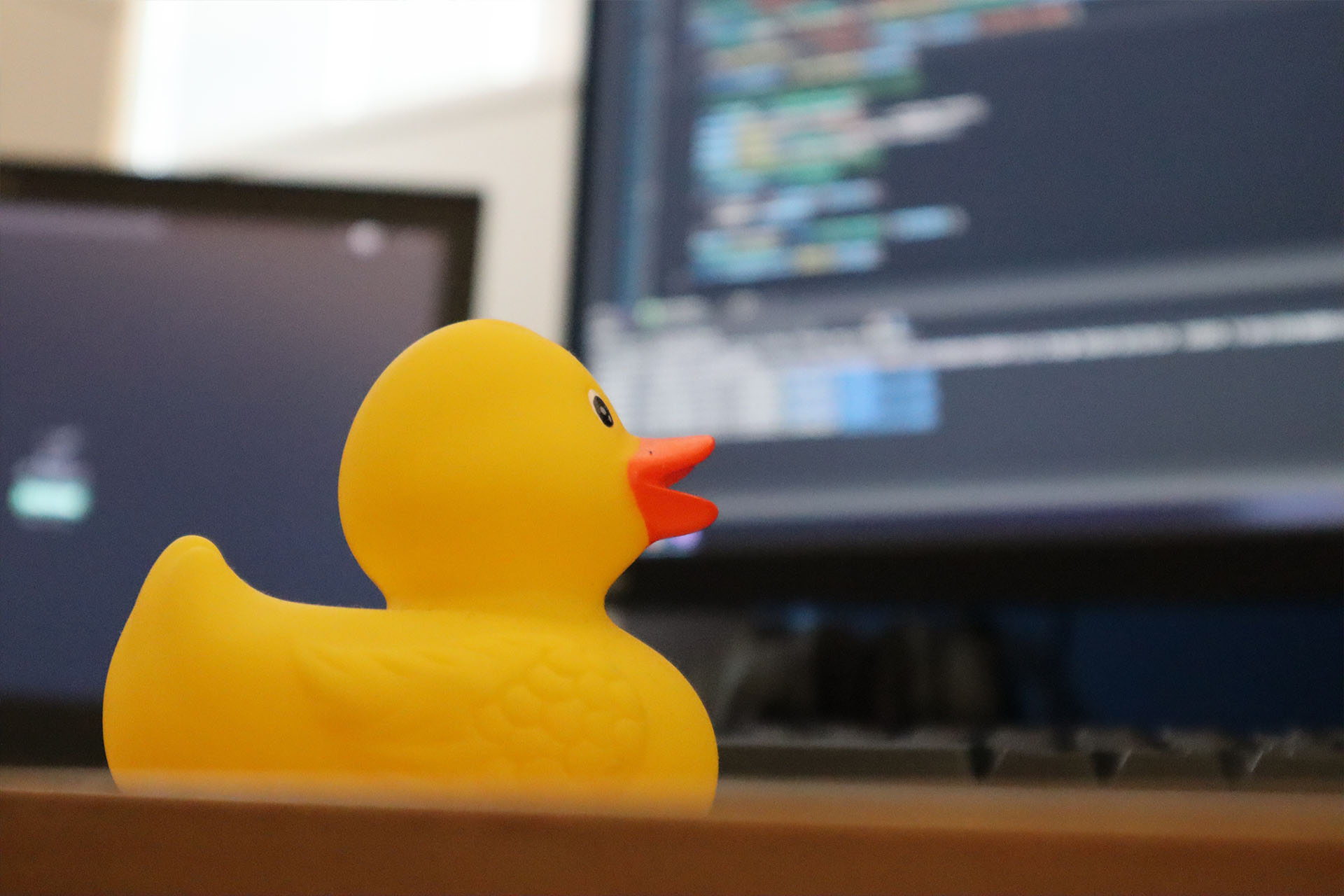A yellow rubber duck in front of code