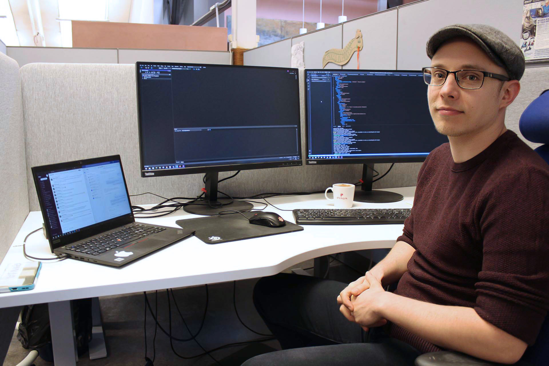 Software developer Roni sitting at his desk in front of two monitors filled with code