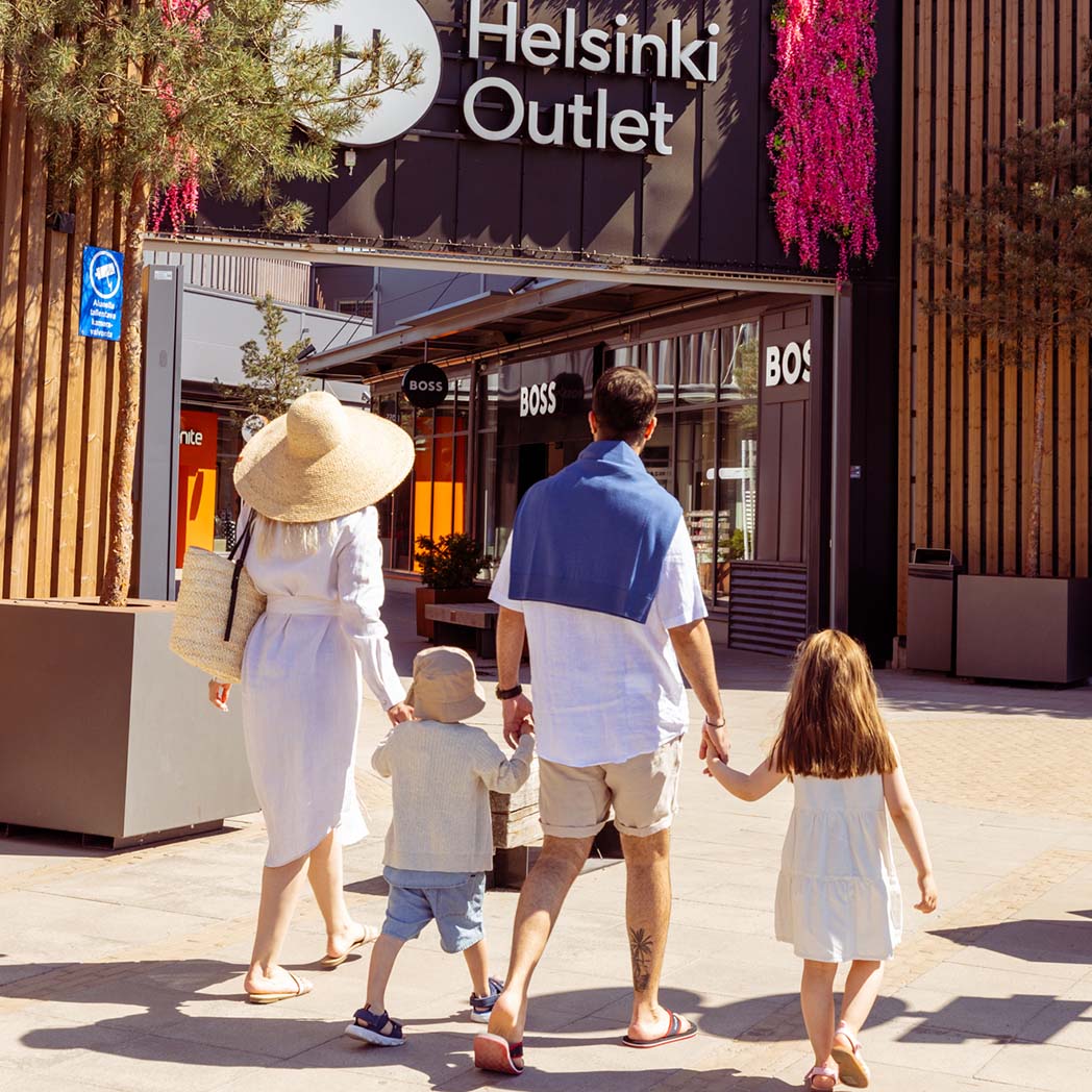 Nelihenkinen perhe kävelemässä käsi kädessä kohti Helsinki Outlet -kylää Nelihenkinen perhe kävelemässä käsi kädessä kohti Helsinki Outlet -kylää